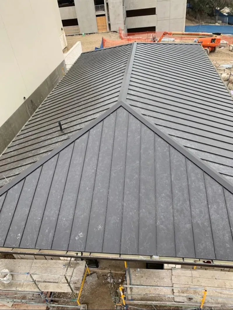 Commercial metal roof construction with crane equipment in Rumford